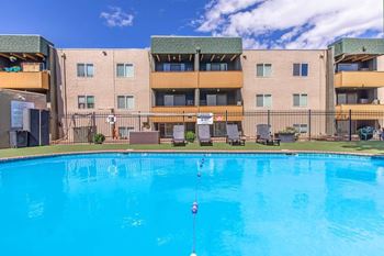 A swimming pool in front of a multi-story apartment building.